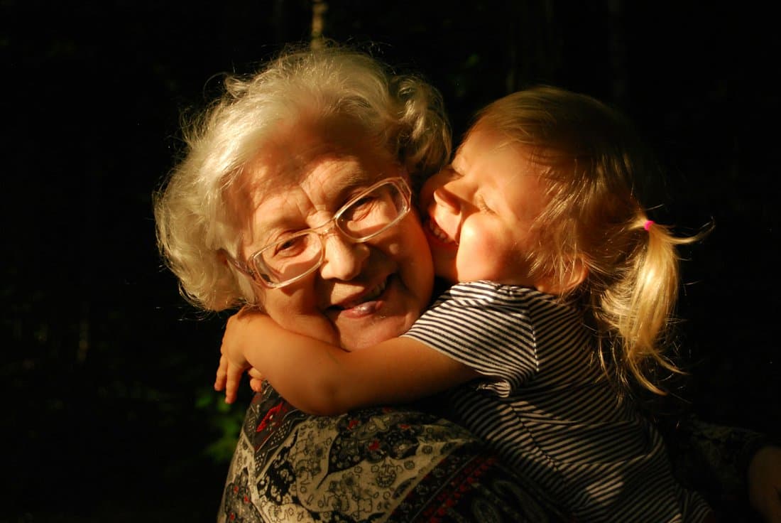 A smiling grandmother hugging her granddaughter