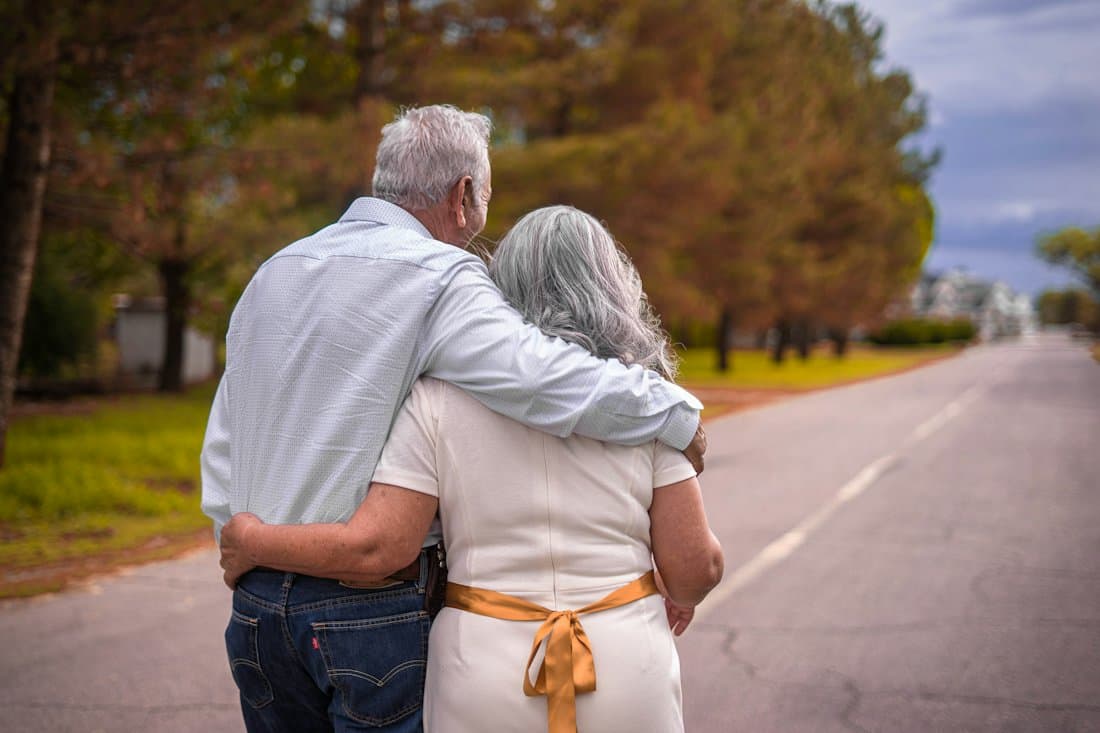 An older couple walking arm in arm down a quiet street